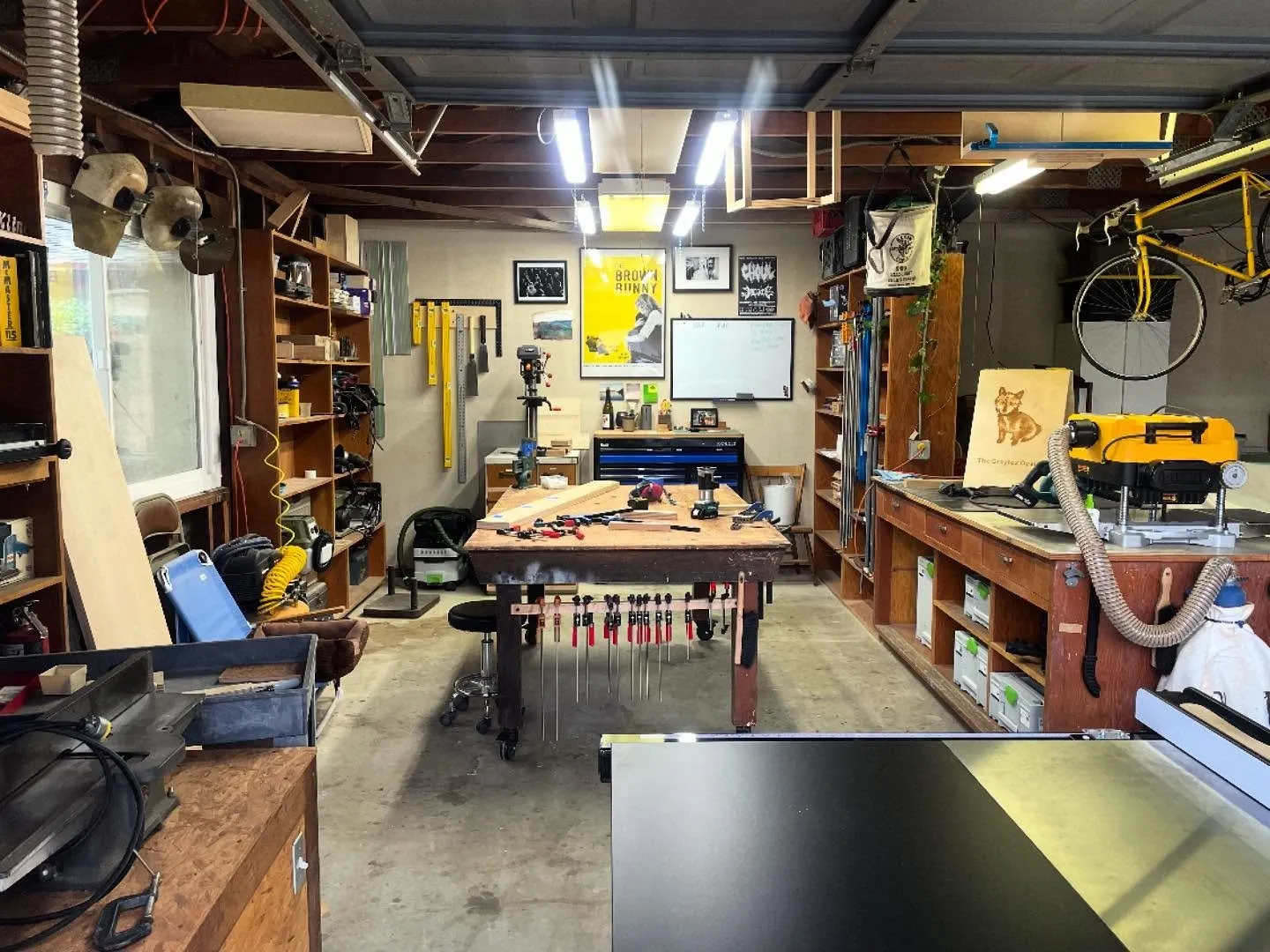 The workshop interior in daylight: benches, hand tools on the wall, and a painted plywood sign bearing the fox mark.